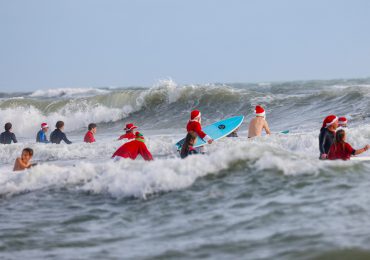 Papás ​​Noel surfistas toman una playa de Florida por diversión y una buena causa