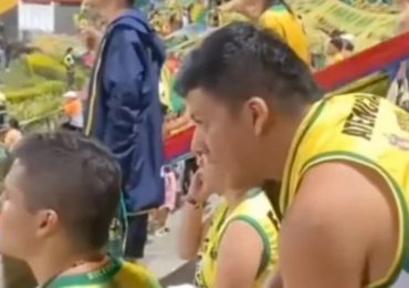 Un fanático de los Bucaramanga de Colombia le explica el partido a su amigo no vidente con los dedos en su espalda